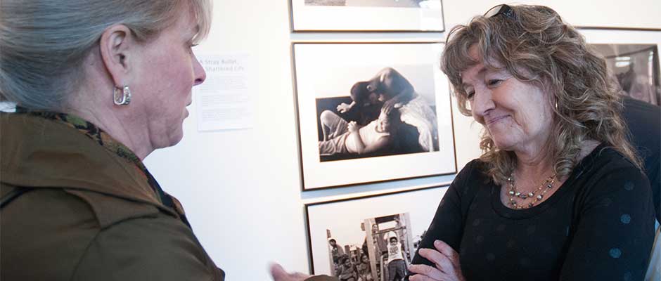 April Saul, right, award-winning photojournalist, chats with a show visitor during her one-night photo exhibit, "Camden, N.J. - A City Invincible," March 20 in Camden.